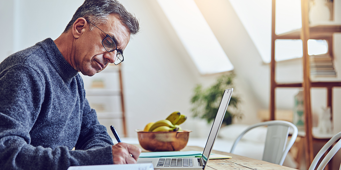 man doing work at desk with laptop and pen